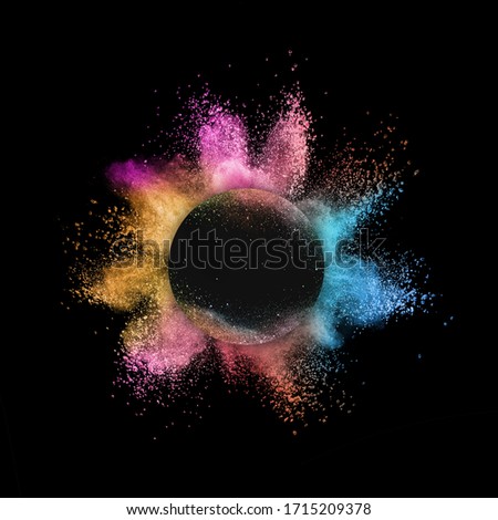 Creative abstract colorful powder explosion or burst in a round frame on a black background with copy space.