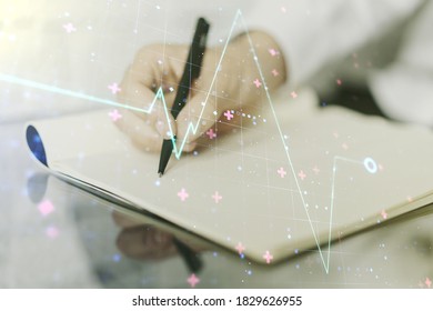 Creative Abstract Heart Pulse Hologram And Man Hand Writing In Diary On Background, Online Medical Consulting Concept. Multiexposure