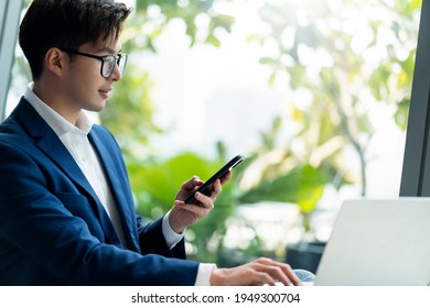 creative agency smart glasses asian male formal cloth conversation with smartphone freelance working with laptop at coworking area office space with freshness with blur office background