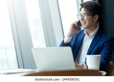 Creative Agency Smart Glasses Asian Male Formal Cloth Conversation With Smartphone Freelance Working With Laptop At Coworking Area Office Space With Freshness With Blur Office Background