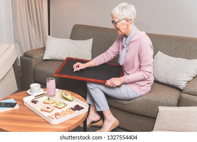 Creative Ambitious Mature Woman Writing To Do List On Blackboard With Chalk While Eating Healthy Nutritious Breakfast, Plans For Today Concept