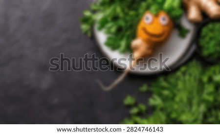 A creative, anthropomorphic vegetable character crafted from ginger and carrot with googly eyes, served on a white plate with fresh greens on a dark slate background.
