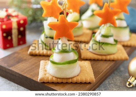 Creative appetizers christmas. Christmas trees of ham, cucumber, cheese and star of carrot on crackers on the festive table.