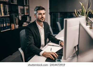 A creative architect is using computer for blueprints at his modern office while looking at monitors.