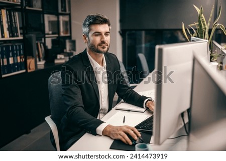 A creative architect is using computer for blueprints at his modern office while looking at monitors.
