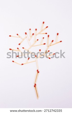 Creative arrangement of matchsticks forms a tree shape on a plain surface during daylight