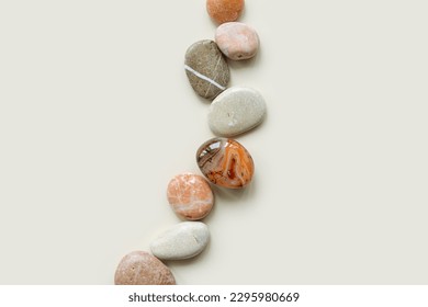 Creative arrangement of natural colored stones. Smooth round pebbles in row on beige background. Minimal trend summer flat lay, top view still life composition with sea rocks and sardonyx, copyspace - Powered by Shutterstock