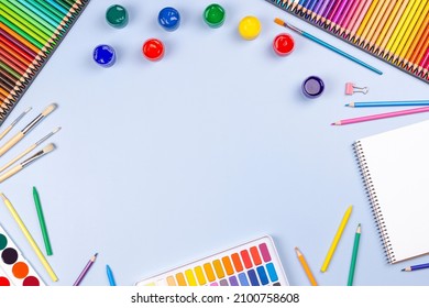 Creative art work supplies background. Watercolor, brushes, pencils, notebook on blue background. Top view, flat lay - Powered by Shutterstock