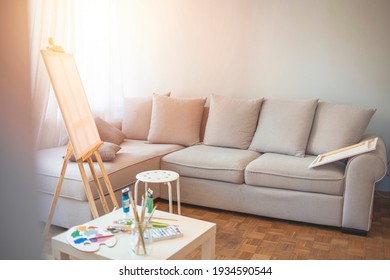 Creative Artist Workplace Room No People HobbyWhite And Bright Studio With A Window. Workspace Of The Artist. Easel, Canvases Easel And Chair Near The Window. 