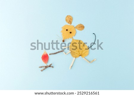 a creative and artistic composition of a mouse made from autumn leaves and twigs on a light blue background. red leaf that looks like a flame, use of natural elements, Dry leaf Animal creature