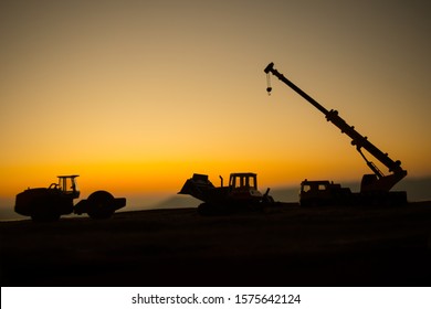 Creative artwork decoration. Construction equipment's silhouette on sunset. Loader truck and mobile crane is coming up hill. Construction concept.