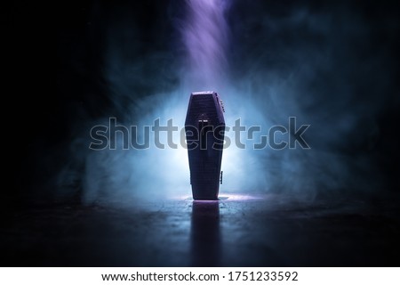 Creative artwork. Miniature wooden coffin on a table with dark background. Selective focus