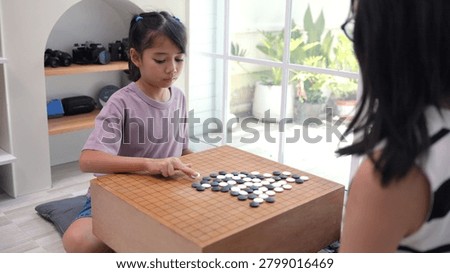 Creative Asian child learner analyzing structural board logic matrix task inside comfortable domestic home living room. Meticulous planning prepares brilliant youths for upcoming scholastic milestone.
