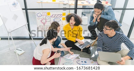 Creative asian team working on new startup project sitting on floor.Asian Business colleague brainstorm share ideas on paper chart with cheerful and enthusiasm successful business teamwork concept
