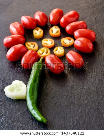 Creative assemblage of vegetables The Scarlet Flower on the black background