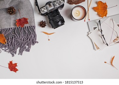 Creative autumn composition on white table. Scarf, camera, candle and yellow leaves, top view