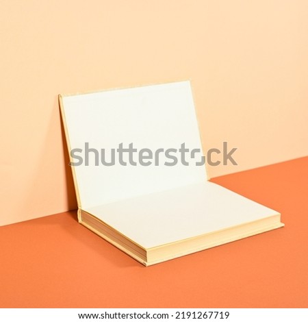 Creative backgorund with open hardcover book on two shade orange background. Flat lay copy space