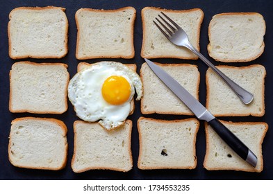 Creative background with fried egg and toast bread. A single fried chicken egg with a fork and knife on a background of pieces of bread. Breakfast at the roadside cafe. Traveling by car, tourism.
