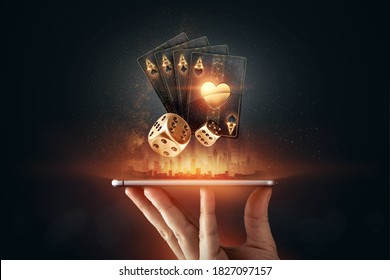 Creative background, online casino, in a man's hand a smartphone with playing cards, roulette and chips, black-gold background. Internet gambling concept. Copy space. - Shutterstock ID 1827097157