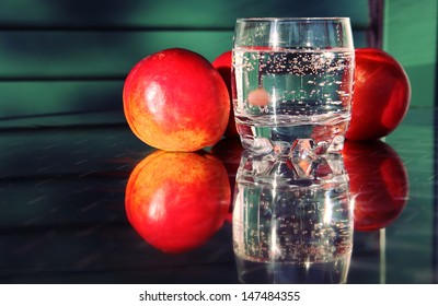 Creative Bar Concept Of Tree Big Nectarines And A Glass Of Sparkling Water On A Reflective Table 