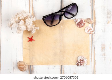 Creative beach-inspired setup with sunglasses, seashells, and a vintage map on a wooden table