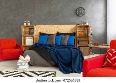Creative bedroom with double bed and red armchairs