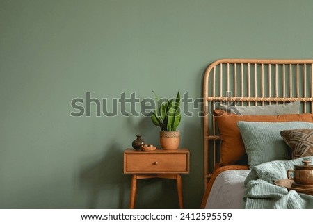 Creative bedroom interior composition with boho style bed, night table, home decorations and personal accessories. Eucalyptus wall. Template. Copy space.