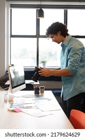 Creative Biracial Young Businessman With Camera At Computer Desk In Office. Unaltered, Creative Business, Workplace, Photography Themes.