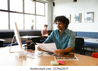 Creative Biracial Young Businessman With Photograph At Computer Desk In Office. Unaltered, Creative Business, Workplace, Photography Themes.