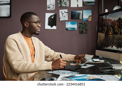 Creative Black man editing photos of landscape on computer when working from home - Powered by Shutterstock