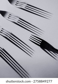 Creative black and white composition of forks with motion blur shadows, forming a dynamic and abstract pattern with movement.
