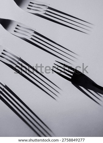 Creative black and white composition of forks with motion blur shadows, forming a dynamic and abstract pattern with movement.