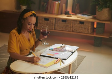 Creative Black Woman Drinking Glass Of Red Wine When Drawing Fashion Sketches For New Season