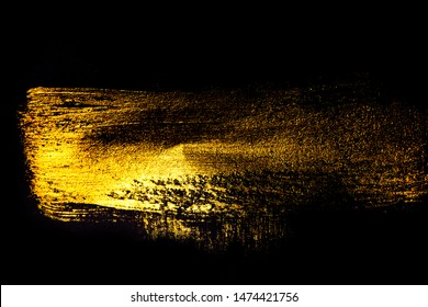 Creative brushstrokes of gold paint isolated on a black background. Gold paint texture.Acrylic gold paint. Smears of cosmetics, blush, highlighter, eye shadow, lipstick.