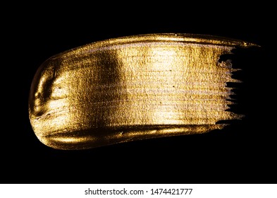 Creative brushstrokes of gold paint isolated on a black background. Gold paint texture.Acrylic gold paint. Smears of cosmetics, blush, highlighter, eye shadow, lipstick.