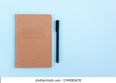 Creative Bullet Journal And Black Pen On Blue Background. Planning And Goal Setting Concept. Place For Text, Top View.