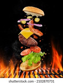 Creative Burger, Flying Layers Of Burger. Well Roasted Patty, Bacon, Cheese And Vegetables On A Flaming Charcoal Grill With Open Fire.