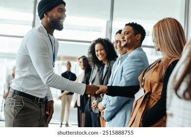 Creative business professionals greeting each other with a handshake in a modern conference setting. Diverse group of people interacting and smiling. - Powered by Shutterstock