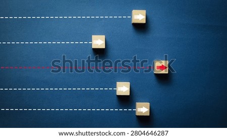 Creative business strategy concept featuring wooden arrow blocks on parallel paths with one standout red direction symbolizing leadership, innovation, differentiation, decision making, competitive advantage, growth, and success.