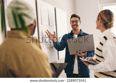 Creative business team having a discussion while standing next to some noticeboards in an office. Group of diverse businesspeople having a meeting in a modern workplace.