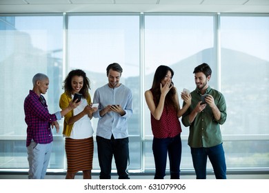 Creative business team interacting while using mobile phone in office