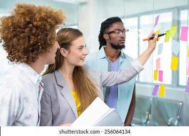 Creative business team pointing at adhesive notes in office - Shutterstock ID 256064134