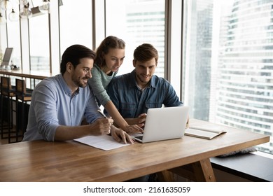 Creative business team sharing laptop in office  watching startup presentation  design project  discussing ideas  brainstorming  pointing at monitor  talking  Office employees meeting at computer