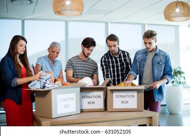 Creative business team sorting clothes in donation box in office - Powered by Shutterstock