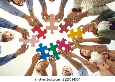 Creative Business Team Trying To Fit Colorful Jigsaw Puzzle Pieces Together, Low Angle Shot From Below, Bottom View. Group Of Happy People Enjoying Teamwork, Finding Solution, Starting New Enterprise