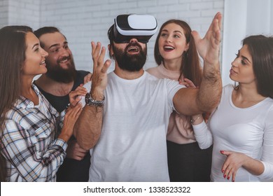 Creative business team using virtual reality glasses at the office. Bearded mature man wearing 3d vr headset, his colleagues surrounding him. Teamwork, startup, innovation concept