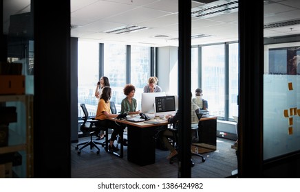 Creative business team working together in a casual office, seen through glass wall - Shutterstock ID 1386424982