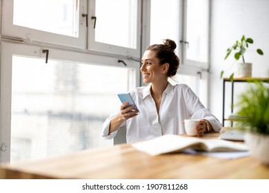 Creative business woman using smartphone in loft office

