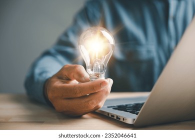Creative businessman holds a light bulb, representing a bright idea. Showcases the concept of innovation, imagination, and successful profit in global business.