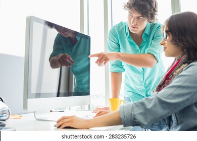 Creative Businessman Showing Something To Colleague On Desktop Computer In Office